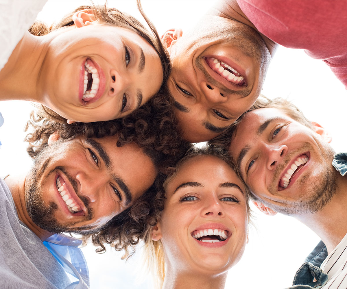 A group of six young adults with smiles, posing together for a photo.